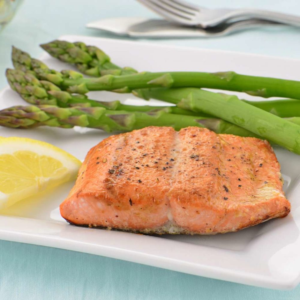 Wild Alaskan Coho Salmon, cooked and plated with asparagus and lemon slices