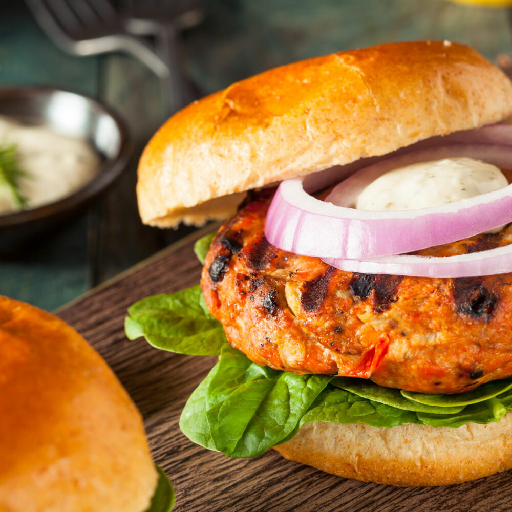 Fire Roasted Tomato Salmon Burger - cooked and served on a bun, with onion and lettuce