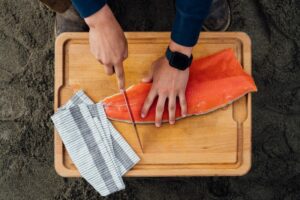 Man cutting a salmon fillet on a cutting board